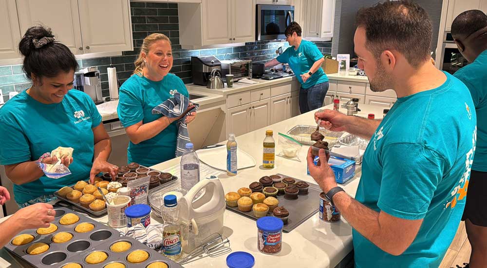 Three people in kitchen decorating cupcakes